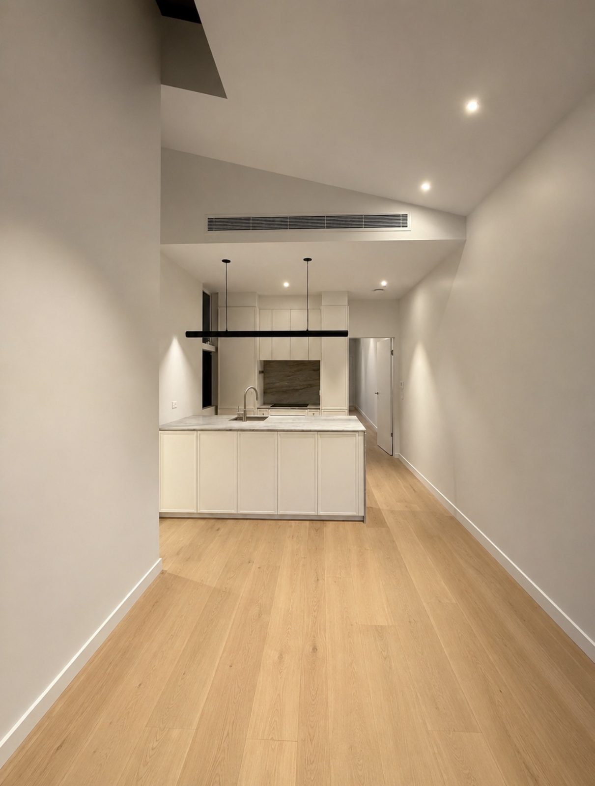Finished open-plan kitchen and living area after an end-of-build clean in Port Melbourne, with clean timber flooring, white island bench and clear stone benchtop