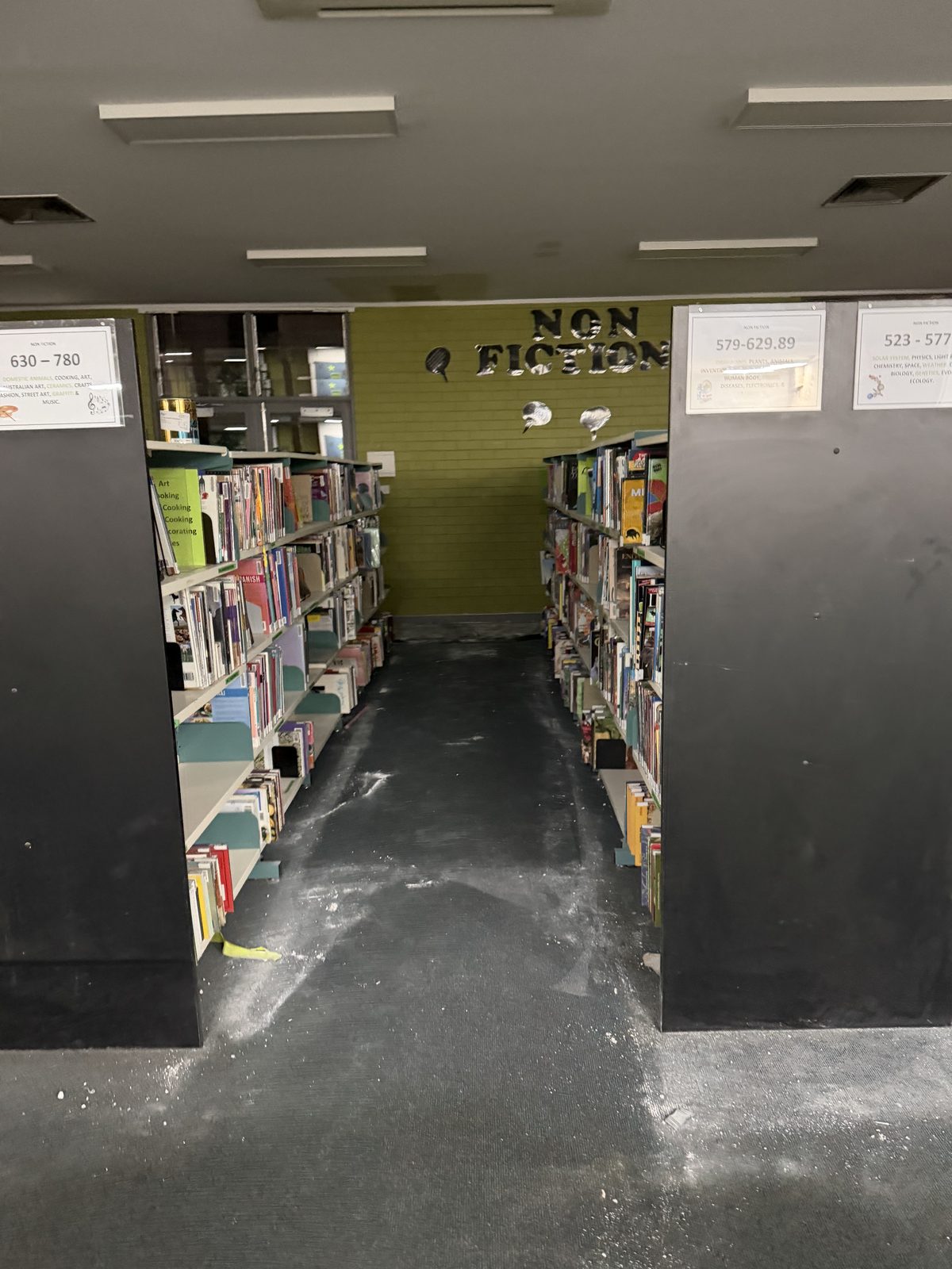 Library shelving aisle in Doncaster with white plaster dust caked across the carpet before the end of build clean